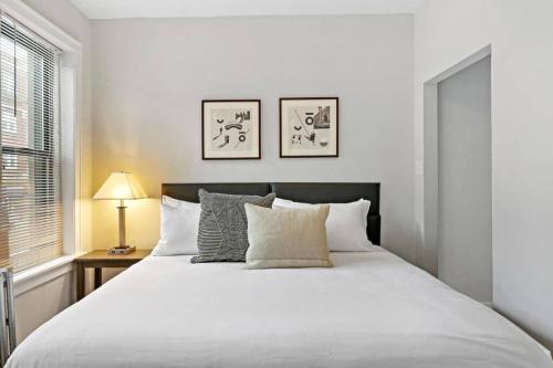 1 dormitorio con 1 cama blanca grande con almohadas en Vibrant & Well-Furnished 2BR Apartment - Roscoe 1A, en Chicago