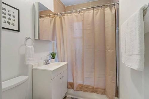 y baño con cortina de ducha y lavamanos. en Vibrant & Well-Furnished 2BR Apartment - Roscoe 1A, en Chicago