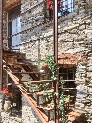 a wooden staircase leaning against a stone wall with plants at La torretta in Pessinetto