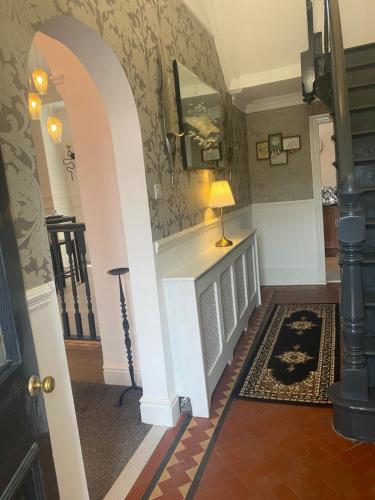 a hallway with a staircase with a lamp on a table at Quigley Buildings - Stylish Entire 2 bed House sleeps 5 Wigan - Private Garden - Free parking - Wifi - Secure garden in Pemberton