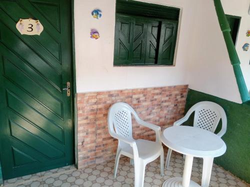 two chairs and a table in front of a door at Pousada Galinhos in Galinhos