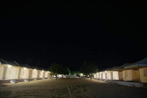 a row of buildings at night with a black sky at Excellent Desert Safari camp in Sām
