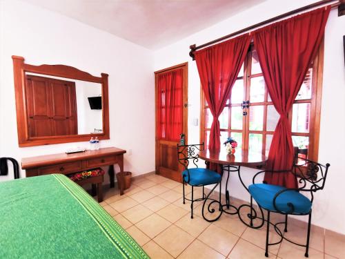 1 dormitorio con mesa, sillas y espejo en Hotel Casa de la Tía Tere, en Oaxaca City
