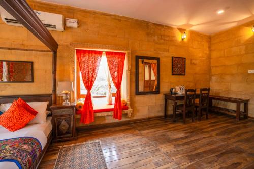 a bedroom with a bed and a desk and a window at Hotel Helsinki House in Jaisalmer