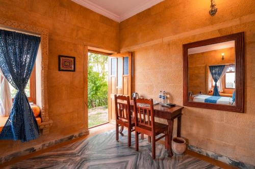 a room with a desk and a mirror and a bedroom at Hotel Helsinki House in Jaisalmer