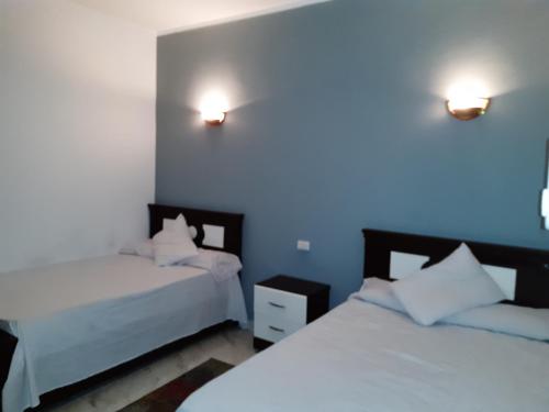 a bedroom with two beds and two lights on the wall at German Dolphin in Quseir