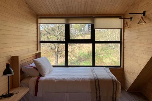 a bedroom with a bed and a large window at Anoka Apart Hotel Boutique in Frutillar