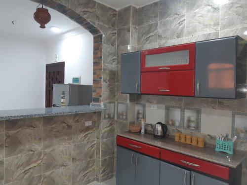 a kitchen with red cabinets and a stone wall at German Dolphin in Quseir