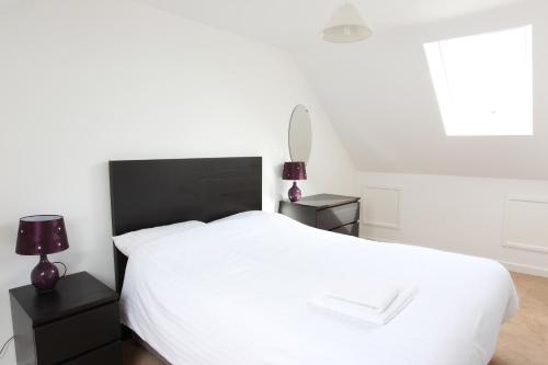 a bedroom with a white bed with two lamps and a window at Elm Tree Farm Accommodation in Milton Keynes