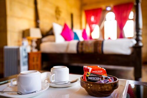a table with two cups of coffee and a bowl of food at Hotel Helsinki House in Jaisalmer