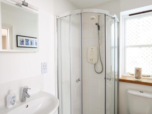 a white bathroom with a shower and a sink at The Chota House in Salcombe