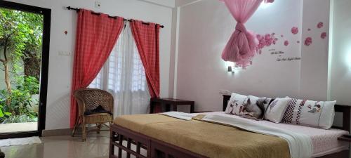 a bedroom with a bed with red curtains and a window at Periyar Inn in Thekkady