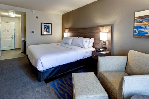 a hotel room with a large bed and two chairs at Holiday Inn Express & Suites Great Bend by IHG in Great Bend