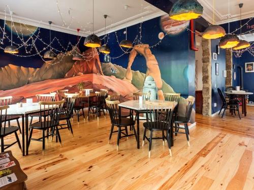 un ristorante con tavoli, sedie e un murale di SUPERNOVA - Hostel & Café a Porto