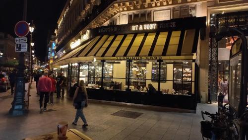 a store on a city street at night with people walking by at Hôtel Paris Nord in Paris