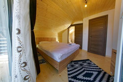 ein Schlafzimmer mit einem Bett und einer Holzdecke in der Unterkunft La Roata Timpului in Câmpulung Moldovenesc