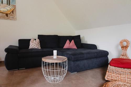 a living room with a black couch and a table at Holzerhof-Ferienwohnungen in Gengenbach