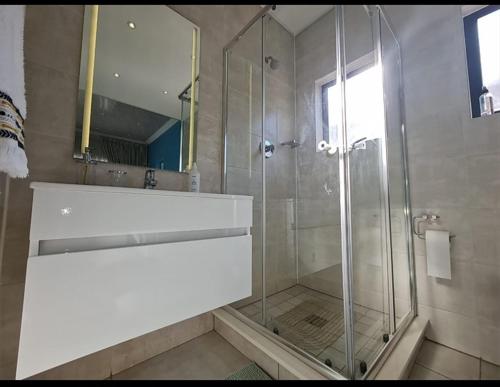 een badkamer met een douche, een wastafel en een spiegel bij Polofields La Bonne Vie in Midrand