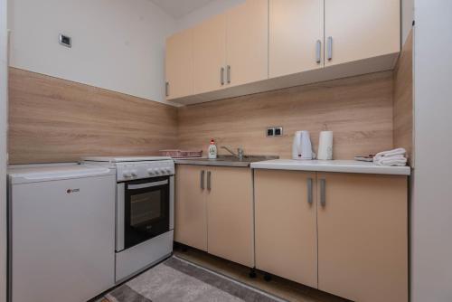 une cuisine avec des appareils électroménagers blancs et des armoires en bois dans l'établissement Elite One Premium Apartment, à Sarajevo