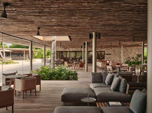 a living room with a couch and tables and chairs at Patina Maldives, Fari Islands in North Male Atoll