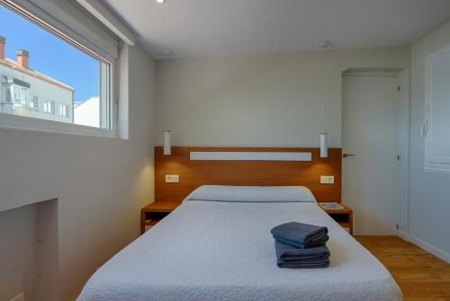 um quarto com uma cama com duas toalhas em Orzan Beach 1 by TheBlueWaveApartments com em La Coruña