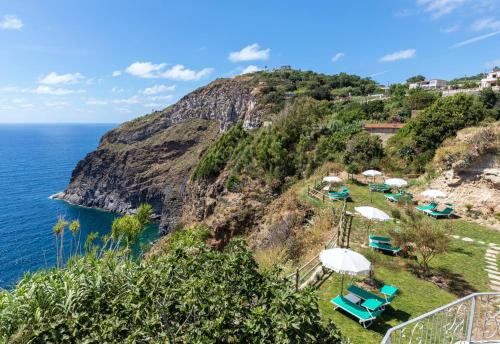 an island with chairs and umbrellas next to the ocean at Hotel Grazia alla Scannella in Ischia