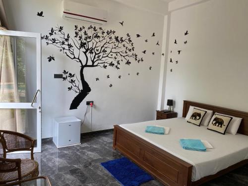 a bedroom with a tree with birds on the wall at Sapphire Garden Hotel in Habarana