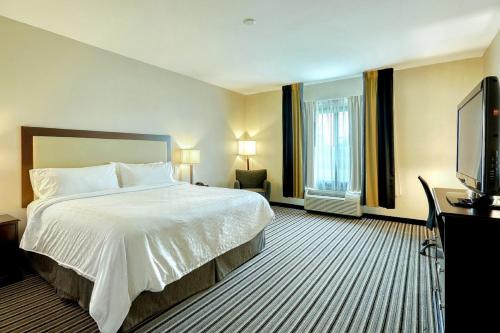 a hotel room with a bed and a flat screen tv at Holiday Inn Express and Suites Batavia by IHG in Batavia