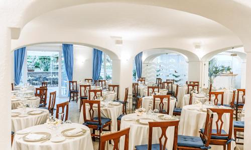 a dining room with white tables and chairs at Hotel Grazia alla Scannella in Ischia