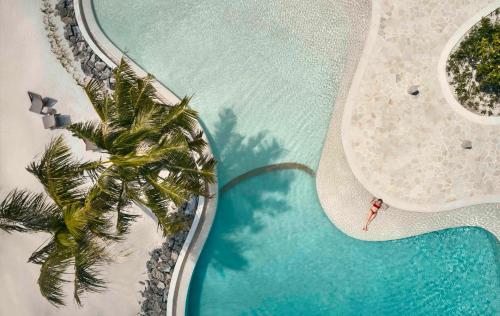 an overhead view of a pool with a surfboard and a palm tree at Patina Maldives, Fari Islands in North Male Atoll