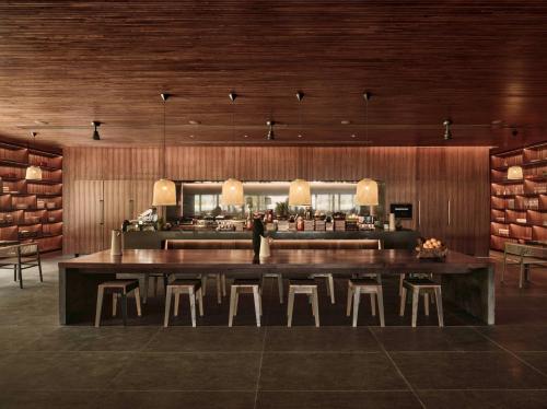 a restaurant with a large table and stools at Patina Maldives, Fari Islands in North Male Atoll