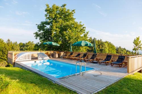 a swimming pool with chairs and umbrellas on a deck at Ferienhaus Pilch Hiasl in Oberhaag