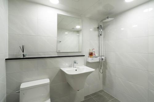 a white bathroom with a toilet and a sink at New Jeju Hotel in Jeju