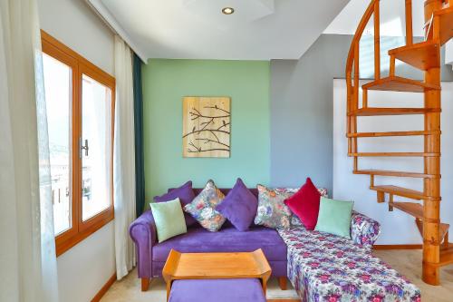 a purple couch with colorful pillows in a living room at Çınarlar Apart Hotel KAŞ in Kas