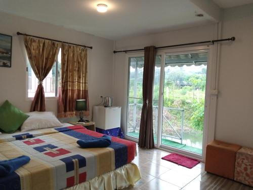a bedroom with a bed and a large window at Lanta Dareen Garden Home in Ko Lanta