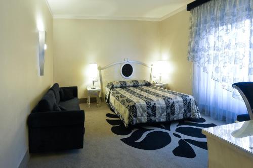 a bedroom with a bed and a chair and a couch at Zanhotel Tre Vecchi in Bologna