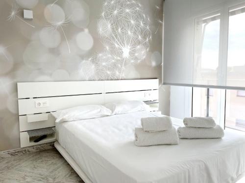 a bedroom with a white bed with two towels on it at Open Sky, Apartamento con solárium privado y barbacoa in El Vendrell