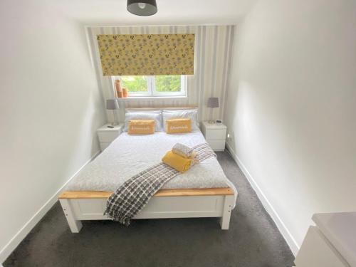 een slaapkamer met een bed met gele kussens en een raam bij Paisley Central Apartment in Paisley