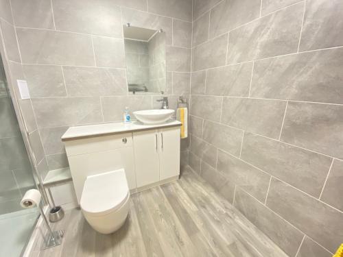 a bathroom with a white toilet and a sink at Paisley Central Apartment in Paisley