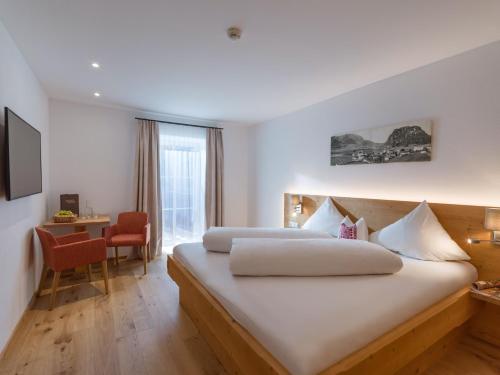 a hotel room with two beds and a desk with a chair at Postgasthof Fischerwirt in Walchsee