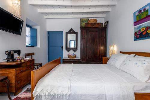 a bedroom with a bed and a dresser and a television at The Aegean blue country house Old Milos in Lagoúdi Zía