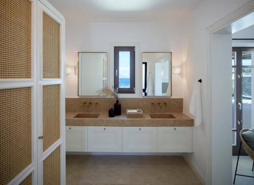 a bathroom with two sinks and two mirrors at Bonzoe Suites & Villas in Mýkonos City