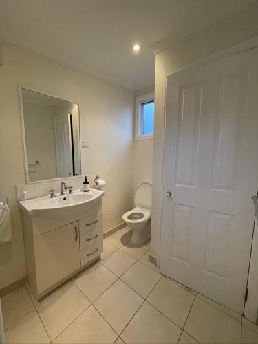 a white bathroom with a sink and a toilet at Shack out the Back in Kyneton