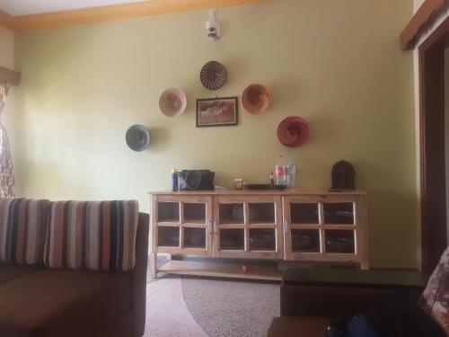 a living room with a wooden cabinet and baskets on the wall at House 1759, near River Nile in Jinja