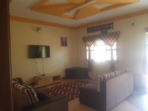 sala de estar con sofá y TV de pantalla plana en House 1759, near River Nile, en Jinja