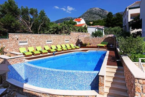 a swimming pool with green chairs next to a building at Boutique Hotel Bol in Bol