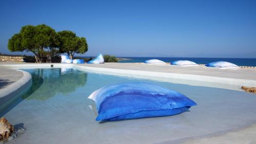 a blue umbrella sitting in the water next to a swimming pool at Eight Dimensions Capari Suites Elafonisos in Elafonisos