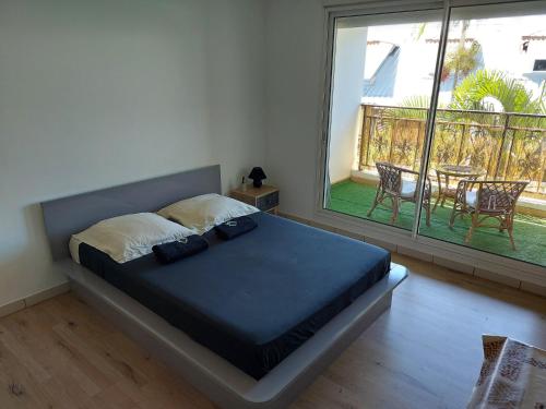 1 dormitorio con 1 cama y balcón con mesa en Studio climatisé proche aéroport, navette en Sainte-Clotilde