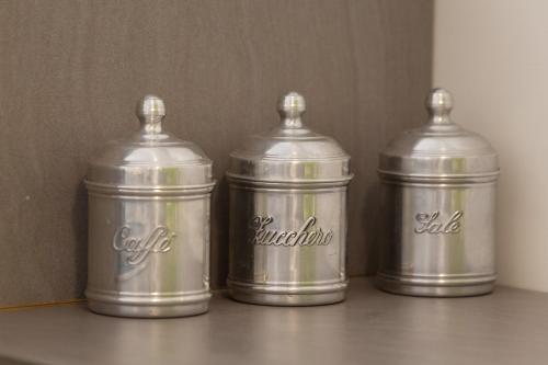 three metal canisters sitting on a table at "Le Casette di Ninetta" - Casa Casmene in Donnalucata