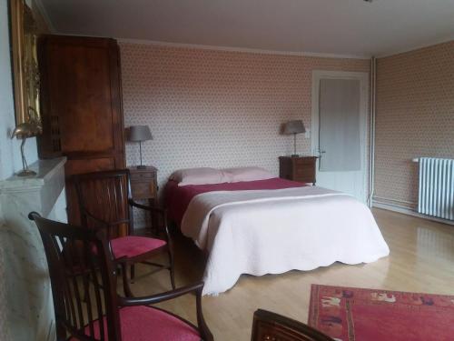 a bedroom with a bed and two chairs in it at Le Clos Marie in Brénod